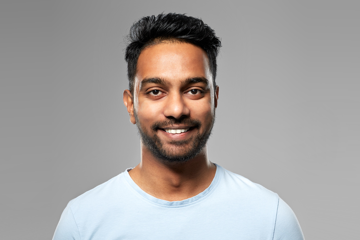 Smiling Young Indian Man over Grey Background